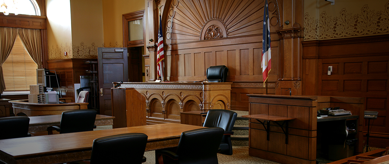 A courtroom with chairs and a table in front of the judge 's bench.